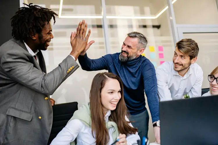 Colleghi in ufficio si danno il 5, simbolo di alta motivazione in azienda | QuBox